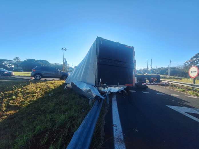 A carroceria de um caminhão-baú que transportava 7 toneladas de papel sulfite tombou na alça de acesso do km 228 da Rodovia Washington Luís (SP-310), em São Carlos