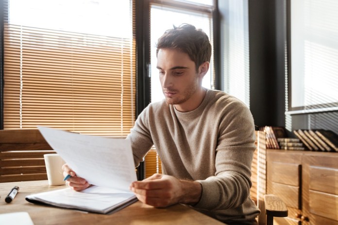 Attractive young man in office working with documents.